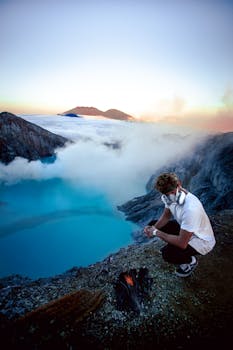 一名男子在硫磺气体的环绕下，观看印度尼西亚卡瓦伊珍陨石坑标志性的蓝色火焰