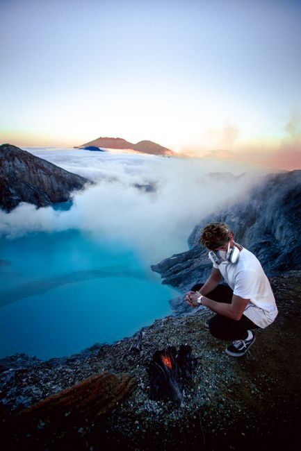 A man watches the iconic blue flames of Kawah Ijen crater in Indonesia, surrounded by sulfur gas.