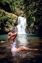在巴厘岛郁郁葱葱的自然风光中，一名女子身着泳衣，在瀑布旁享受宁静的时刻