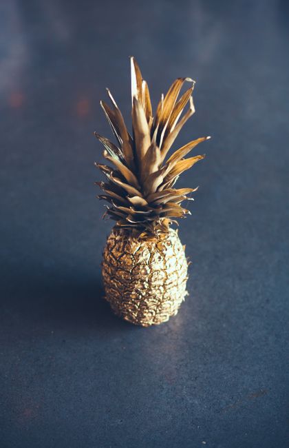A single golden pineapple stands out against a dark surface, creating a striking visual.