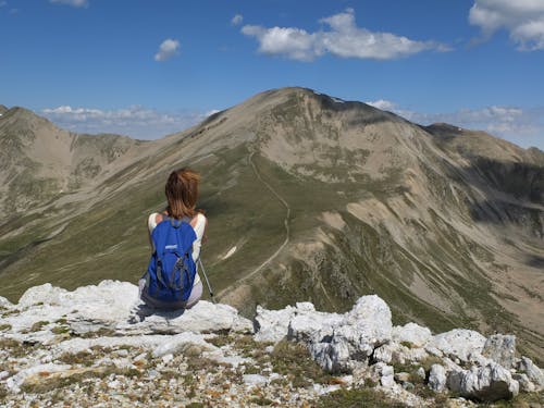 免费 女人坐在山的岩石前面 素材图片