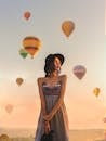 日出时分，一名戴着太阳帽的妇女被彩色热气球包围，构成了一幅宁静的画面