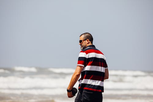 Free Man In Striped Shirt Near Body Of Water Stock Photo