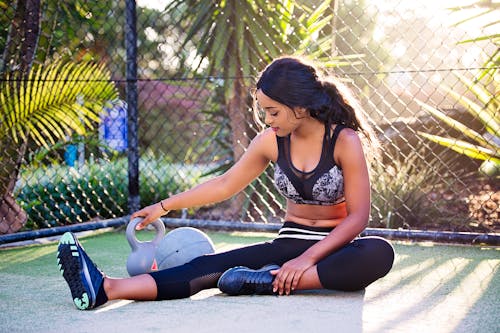 Woman Sitting Holding Holding Grey Kettle Bell