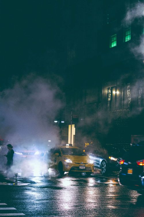 Free Dynamic city street scene with cars, headlights, and steam at night. Stock Photo