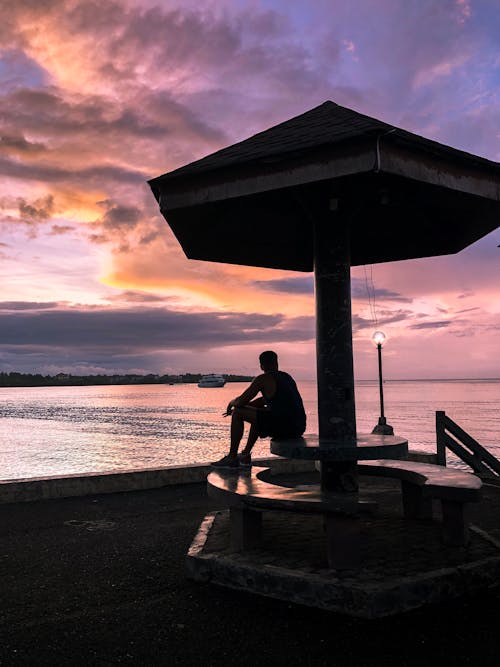 Uomo Seduto Sul Tavolo A Guardare La Vista Del Tramonto