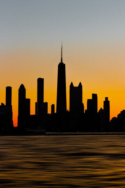 Silhouette of the Chicago skyline against a vibrant sunset, highlighting skyscraper outlines.