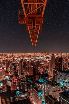 A breathtaking aerial view of a city at night with a crane overlooking a sea of city lights.
