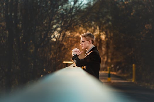 日落时分，一名西装革履的男子在公园的桥上若有所思地凝视着金色的余晖