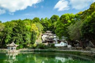 绿树成荫的清澈湖水旁，呈现出中国传统建筑的宁静景象