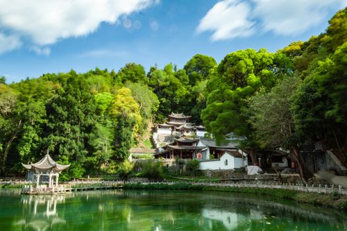 Free Tranquil scene of traditional Chinese buildings by a clear lake surrounded by lush greenery. Stock Photo