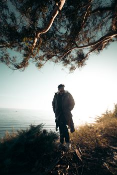 日落时分，一名穿着外套的男子站在戈莱塔的海边，反思着大自然