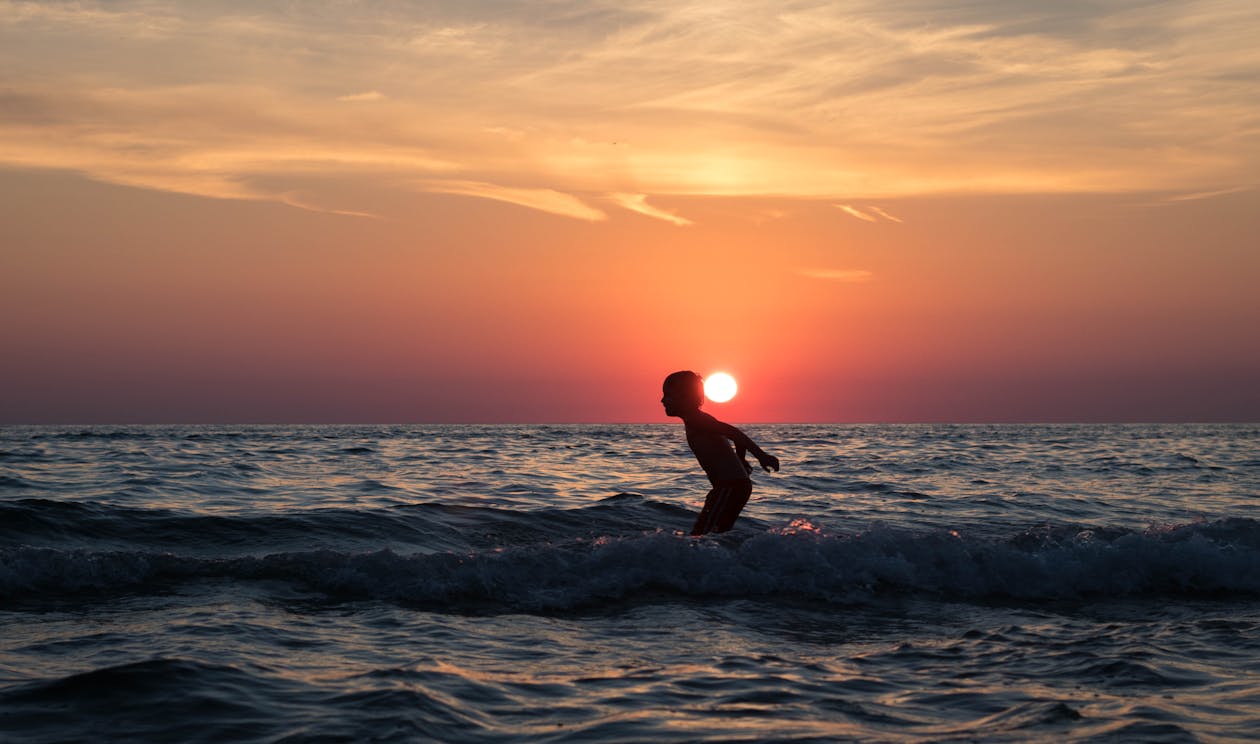 無料 日没時に水域に囲まれた男のシルエット 写真素材
