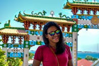 一位戴着墨镜的女人在色彩缤纷的亚洲传统寺庙门前微笑