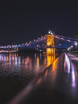 迷人的夜色中，一座照明吊桥映照在平静的河水上