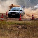 一辆汽车在土路上行驶，扬起灰尘，从交通锥上飘过