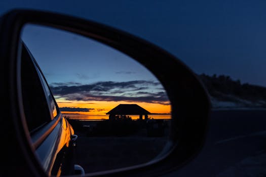 车侧镜中映照着宁静的日落，背景是风景