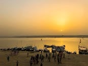 河上日落宁静，岸边船只和人员聚集，风景如画