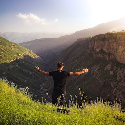 무료 푸른 잔디 산에 서있는 동안 팔을 펼친 남자 스톡 사진