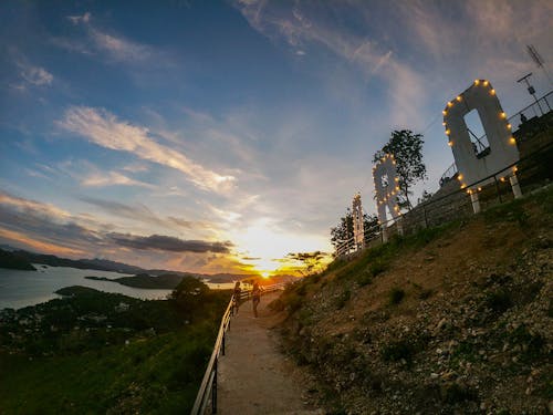 Photo of Two Women Standing on Paved Pathway During Golden Hour