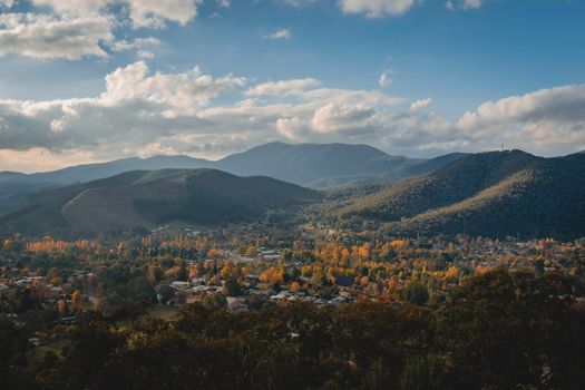 Explore the breathtaking scenery of Bright, Victoria with lush greenery and majestic mountains under a vivid sky.