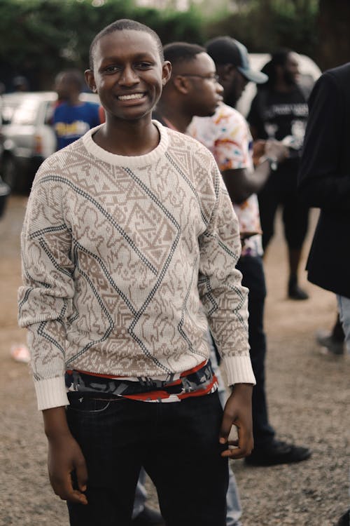 Photo of Smiling Man Posing With People in the Background