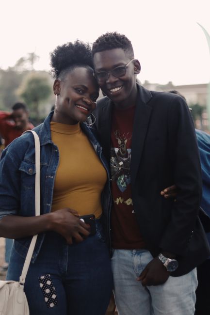 Happy couple in casual fashion smiling outdoors, embracing and showcasing affection.