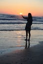 日落时分，一名女子在海滩上摆出富有创意的剪影姿势