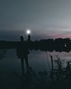 黄昏时分，湖边剪影的人提着灯，月光映照其上