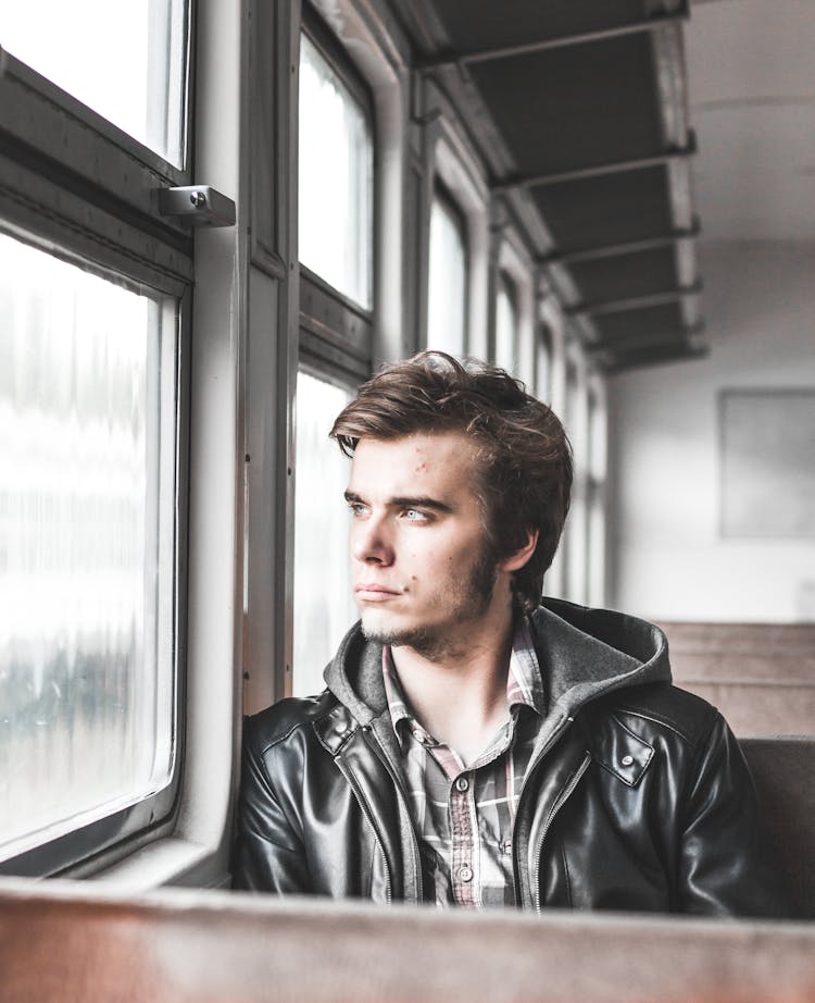 Photo Of Man Sitting In Train Looking Outside Window