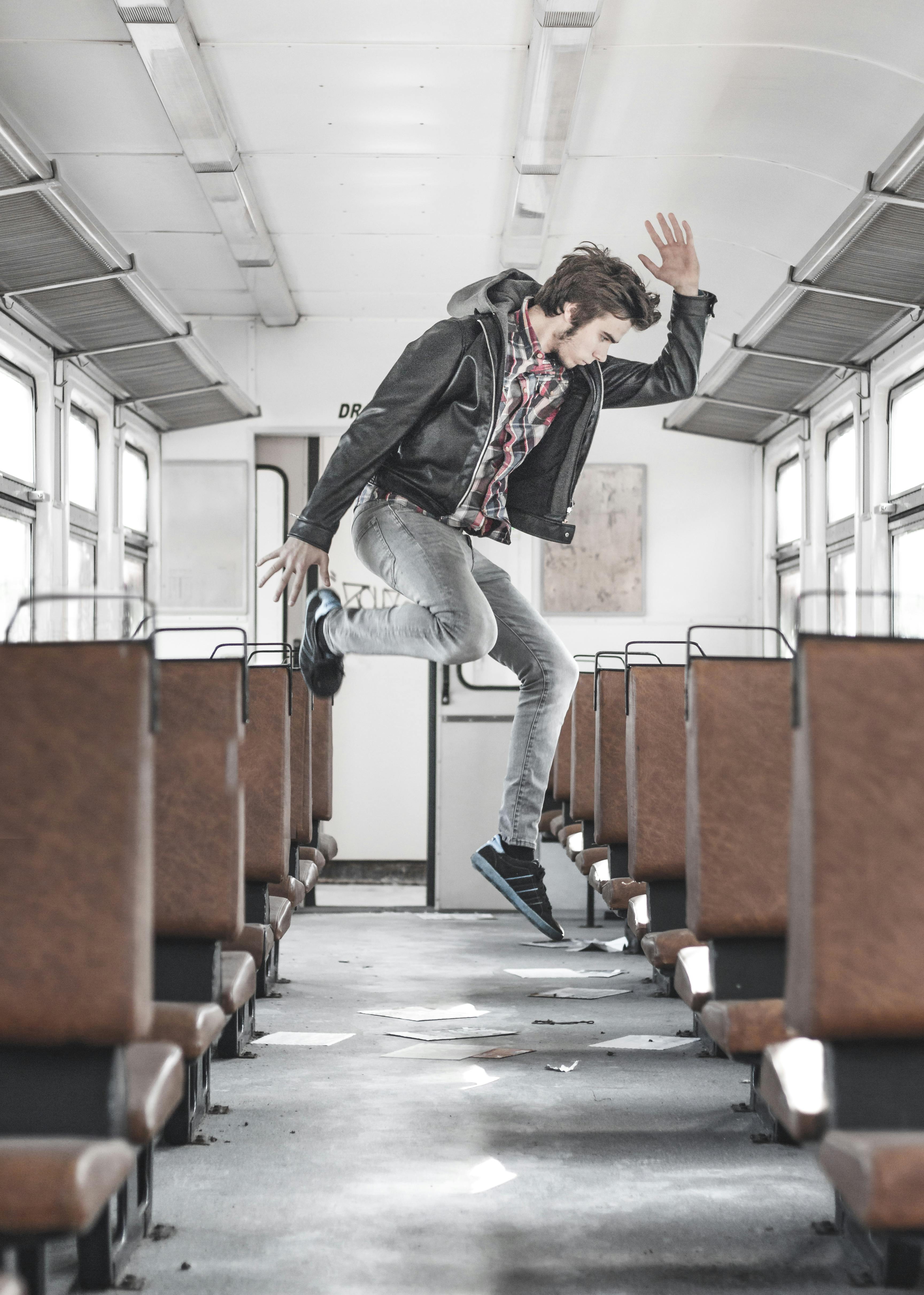 Side View Photo of Man Jumping Inside Train Aisle · Free Stock Photo