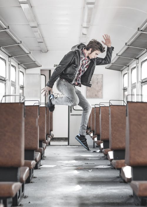 Free Side View Photo of Man Jumping Inside Train Aisle  Stock Photo