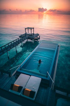 Experience ultimate relaxation at a luxury Maldives resort with an infinity pool overlooking the ocean at sunset.