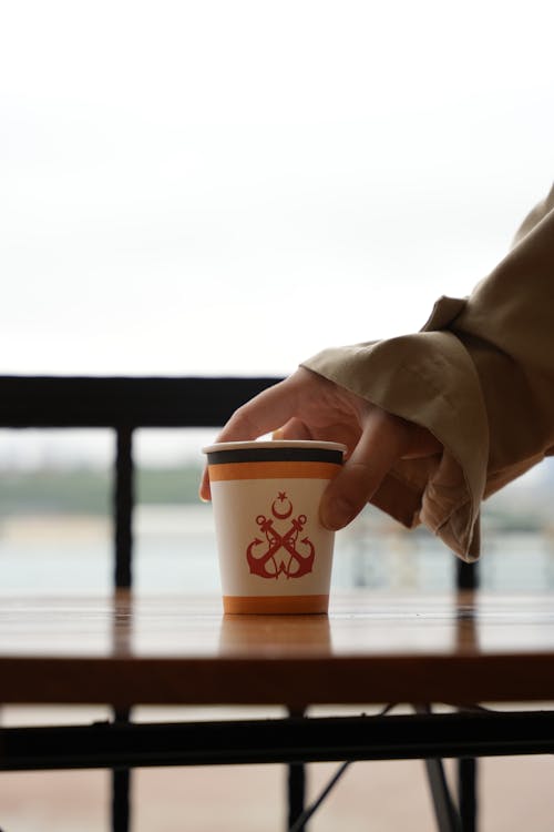 A person holding a cup with a red logo on it