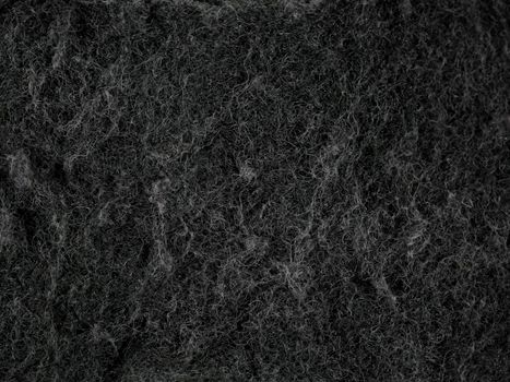 Detailed texture of a black dish sponge captured in macro photography, emphasizing fiber details.