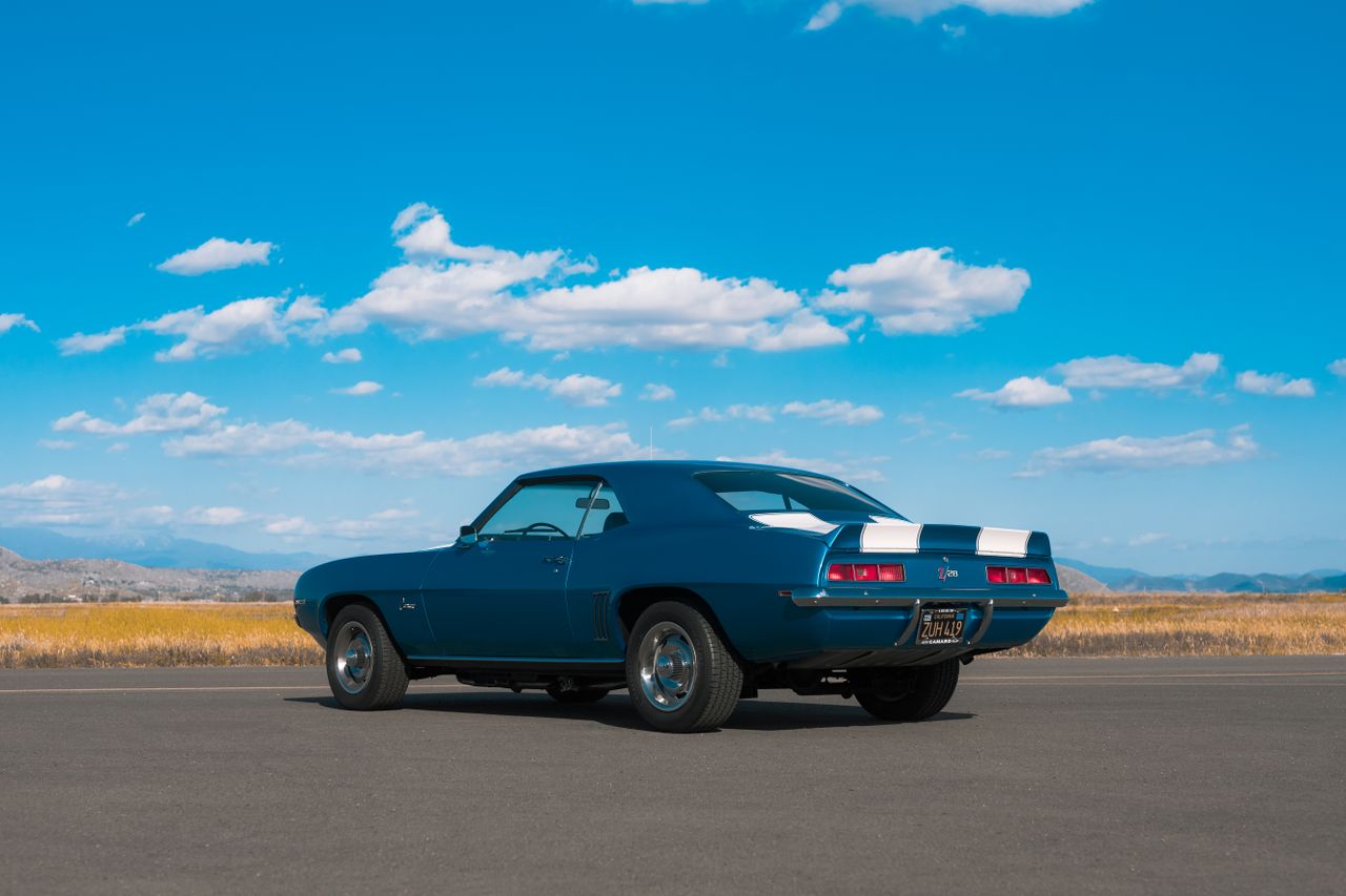 blue 1969 chevrolet camaro parked on asphalt under a clear blue sky