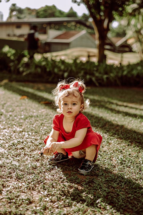 Free A Little Girl Crouching in a Garden  Stock Photo