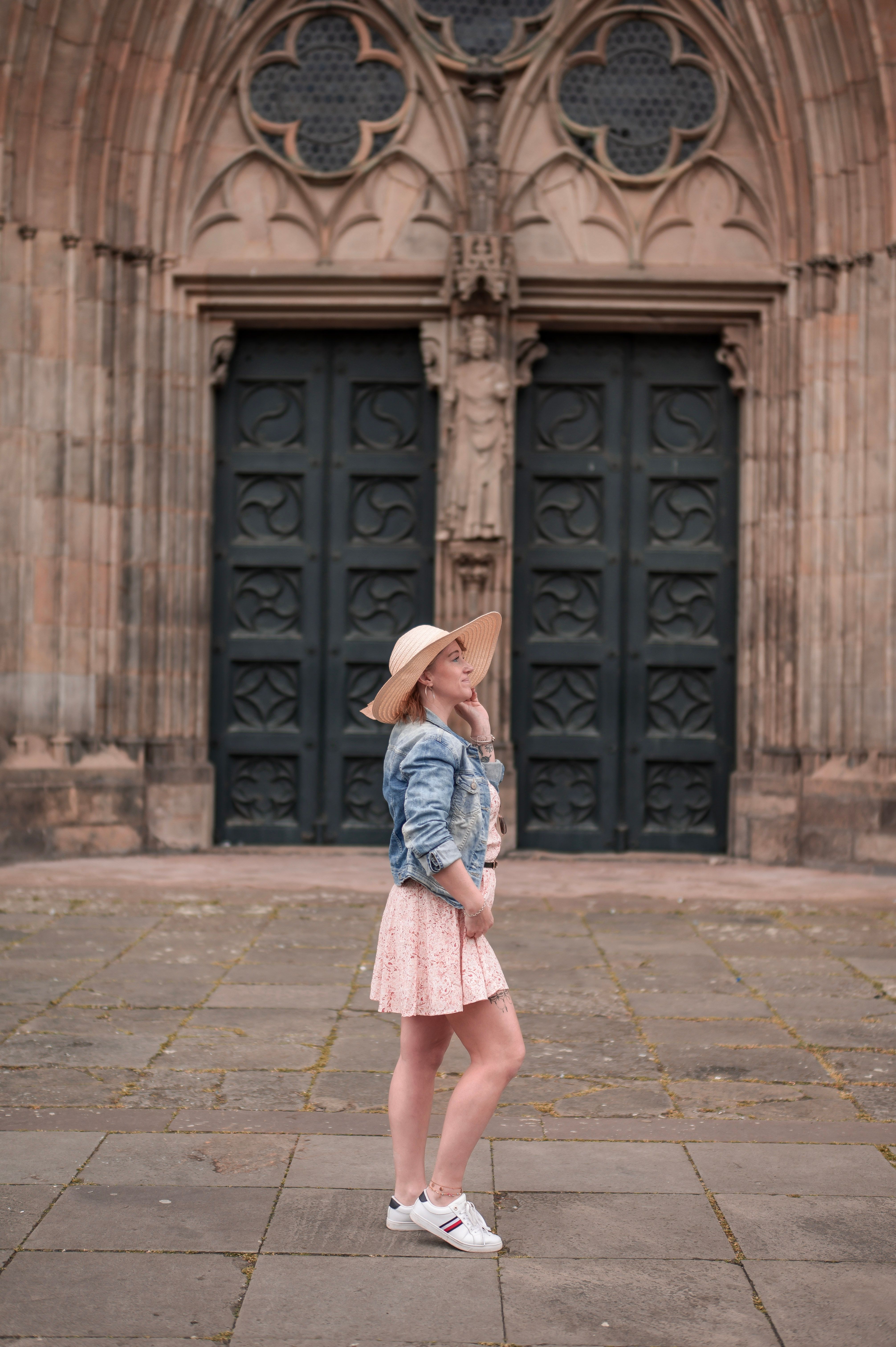 Stylish woman in hat and jacket standing in front of the iconic Magdeburg Cathedral facade.