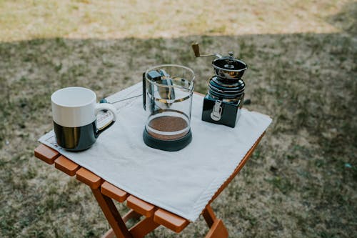 A coffee pot sits on a table next to a cup and a mug