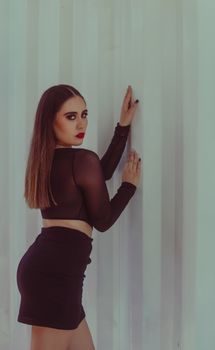 Stylish woman in black outfit posing against light background, showcasing modern fashion.