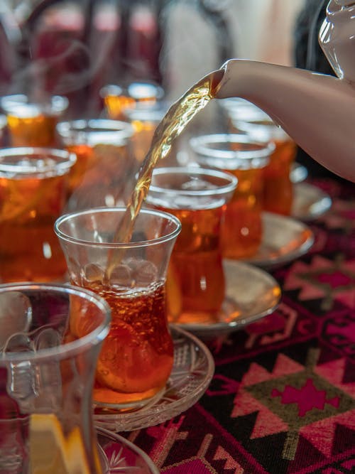 A person pouring tea into cups on a table