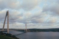 阴沉的天空下，吊桥横跨平静的水面，景色令人惊叹