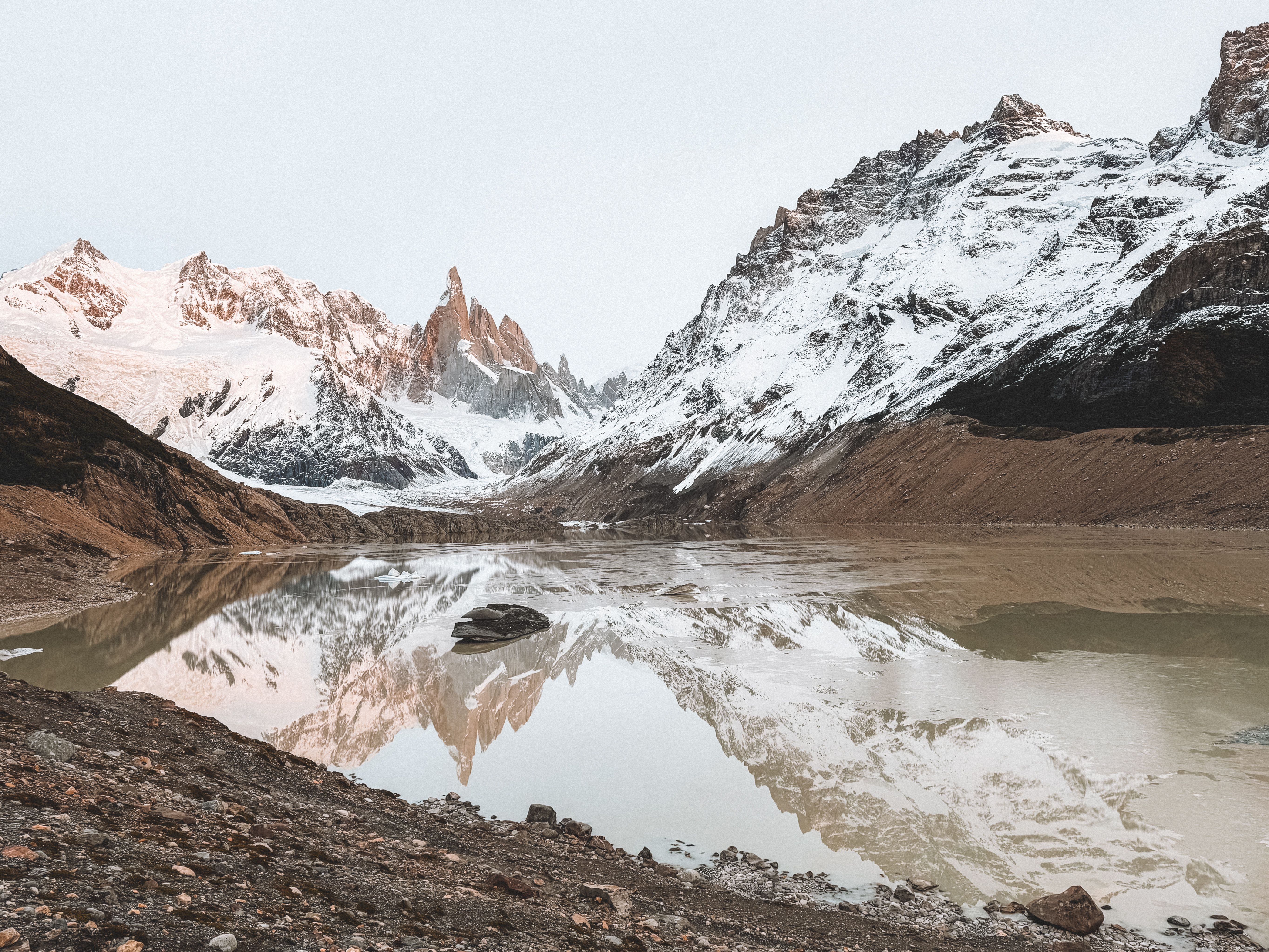 Snow-covered alpine valley stream, wide mountain vista