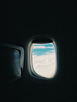 A serene view of sky and clouds from a plane window, offering a glimpse of the travel experience.
