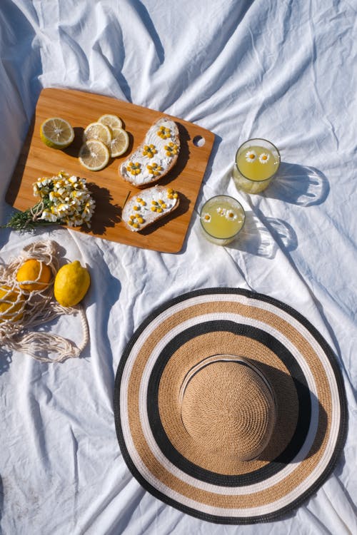 Food, Drinks and a Sunhat on a Blanket in Sunlight