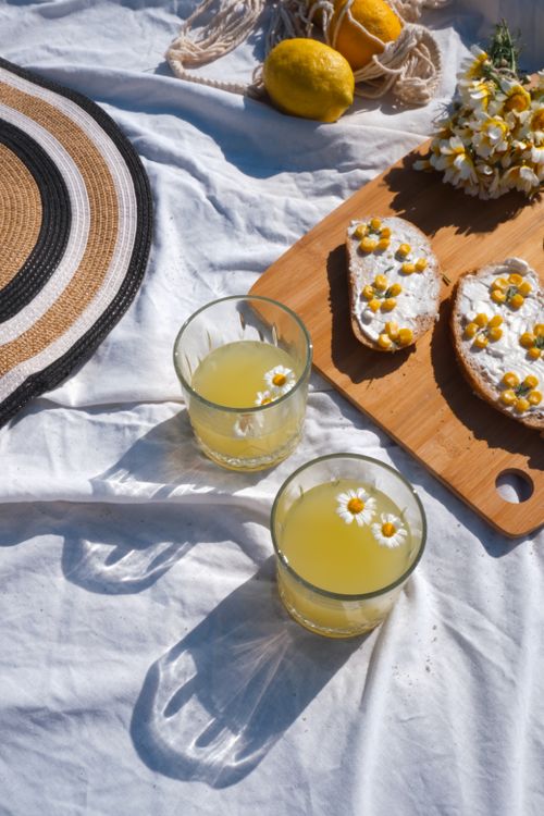 Free Bright summer picnic setup with chamomile lemonade and snacks on a wooden board. Stock Photo