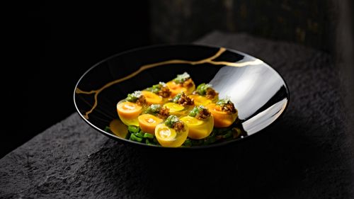 Free An elegant gourmet dish featuring yellow tomatoes with garnishing on a designer plate. Stock Photo