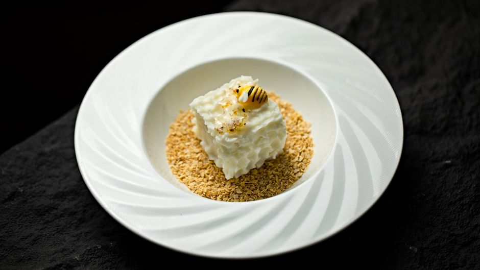 A glass bowl of pale, fluffy snow cream topped with a light dusting of sugar, with a snowy window visible in the background.