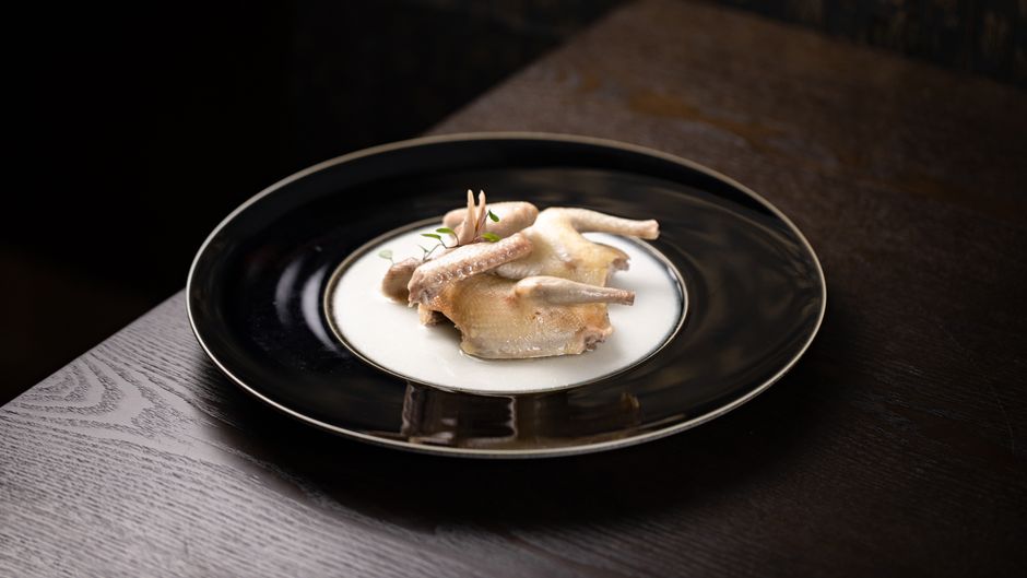 Two golden-brown roasted Cornish hens on a platter with lemon halves and fresh thyme sprigs, skin glistening and crisped at the edges.
