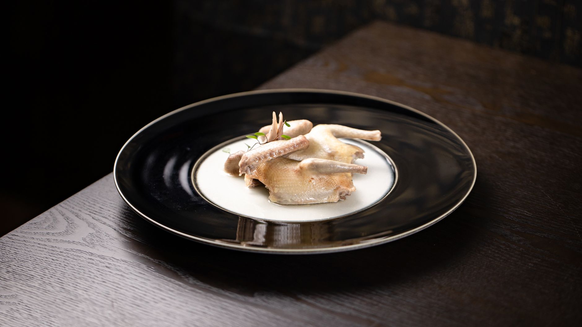Exquisite fine dining presentation of cooked chicken on a stylish black plate.